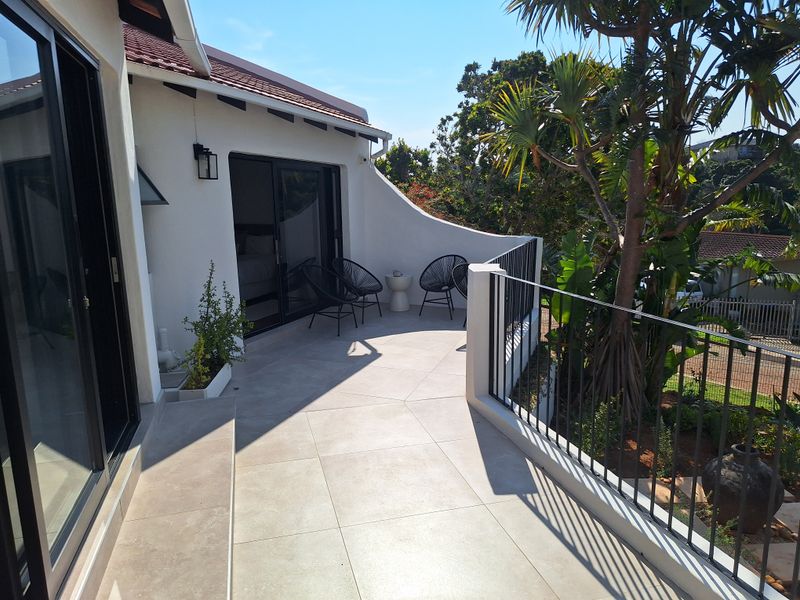 A well-maintained balcony featuring modern tiled flooring, a secure metal balustrade, and sliding glass door access to the interior.