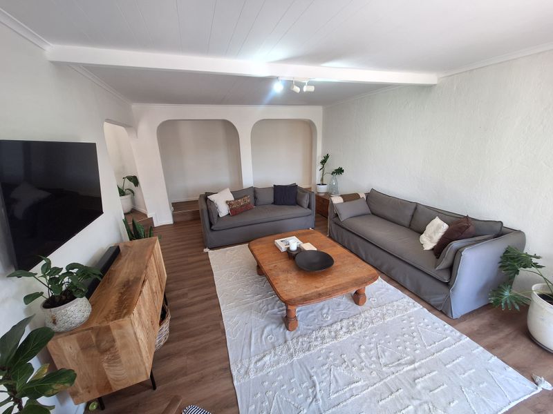 A bright and spacious living room featuring arched architectural details, laminate flooring, and a clean, neutral aesthetic with modern track lighting.