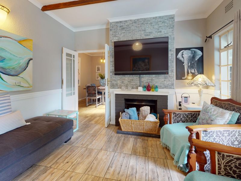 A cozy living room featuring a stone-clad fireplace, tiled flooring, and double doors leading to an adjacent dining area.