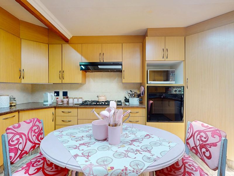 A functional kitchen featuring light wood-tone cabinetry, granite countertops, and integrated appliances including a gas hob, oven, and microwave.