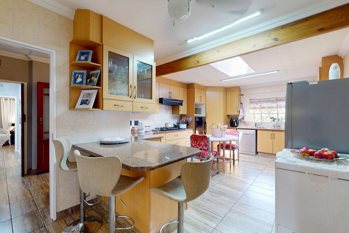A functional kitchen featuring light wood cabinetry, granite countertops, a breakfast nook, and a skylight, providing a bright and practical workspace.