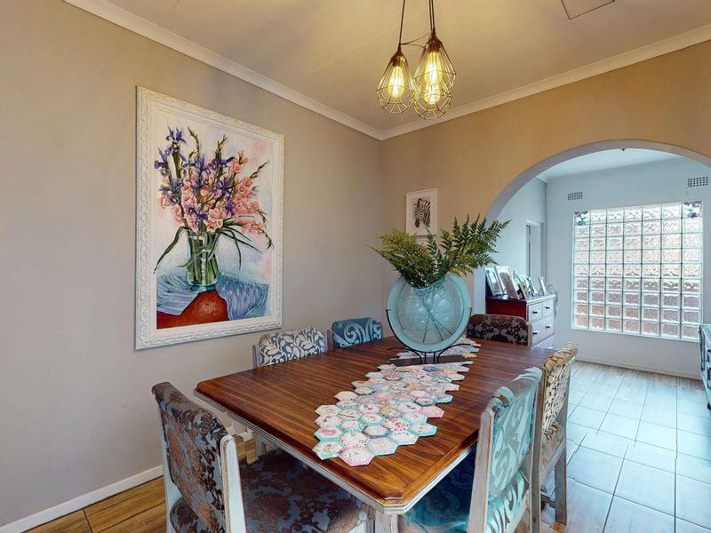 A well-lit dining room featuring an elegant archway leading to an adjacent space, finished with tiled flooring and decorative pendant lighting.