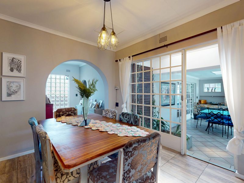 A well-lit dining room featuring tiled floors, an elegant archway, and large glass sliding doors that provide a seamless transition to the adjacent living space.