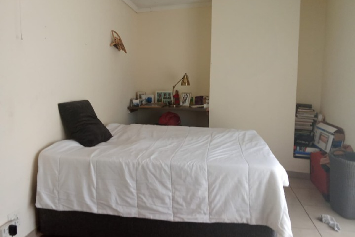 A bedroom featuring tiled flooring and a built-in shelving alcove, offering a functional space with potential for cosmetic updates.