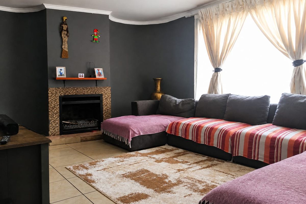 A comfortable living room featuring a built-in fireplace with mosaic tile surround, tiled flooring, and coved ceiling details.