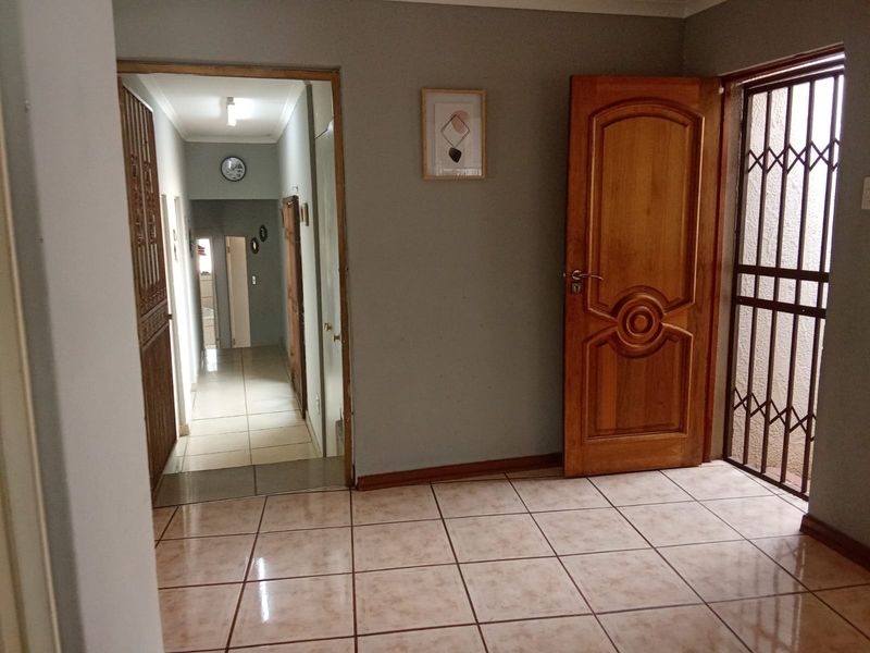 A tiled hallway area featuring a timber door and a security gate, providing access to the interior living spaces.