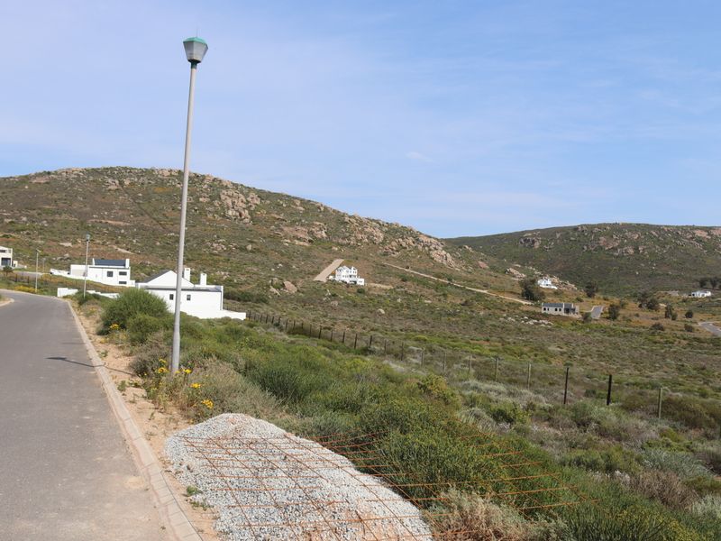 A view of the paved street and surrounding landscape in a residential estate, featuring established infrastructure and nearby hillside homes.