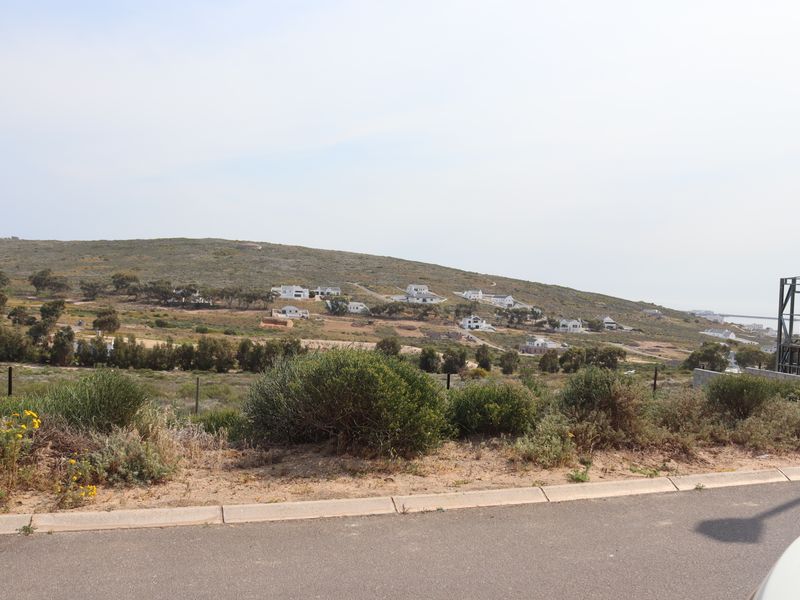 A scenic view of the surrounding landscape and hillside residential area from the street level of the vacant residential plot.