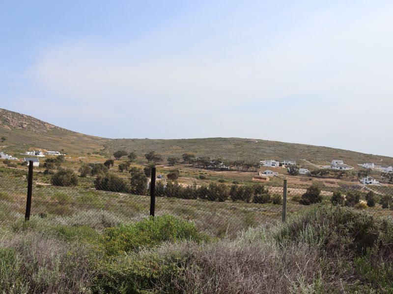 A wide-angle view of the surrounding hillside landscape and residential development, captured from behind a wire mesh fence.