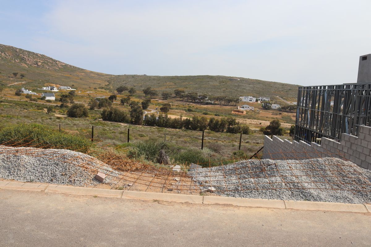 A view of the surrounding landscape from a residential plot featuring an unfinished steel frame structure and construction materials on site.