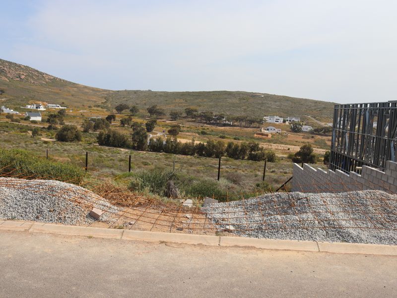 A view of the surrounding landscape from a residential plot featuring an unfinished steel frame structure and construction materials on site.