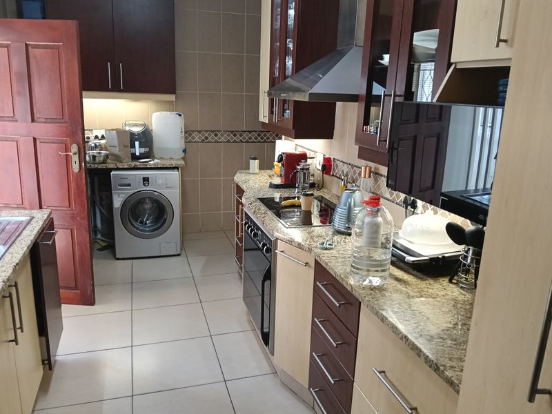 A functional kitchen featuring granite countertops, built-in cabinetry, an integrated oven and hob, and tiled finishes throughout.