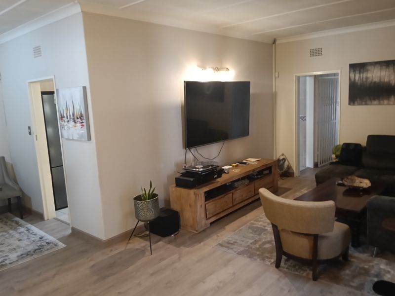 A comfortable living room featuring laminate flooring, coved ceilings, and a wall-mounted television setup with integrated lighting.
