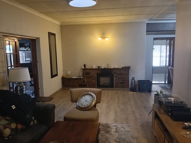 A living room featuring a brick fireplace, laminate flooring, and neutral wall finishes, providing a functional and comfortable space.