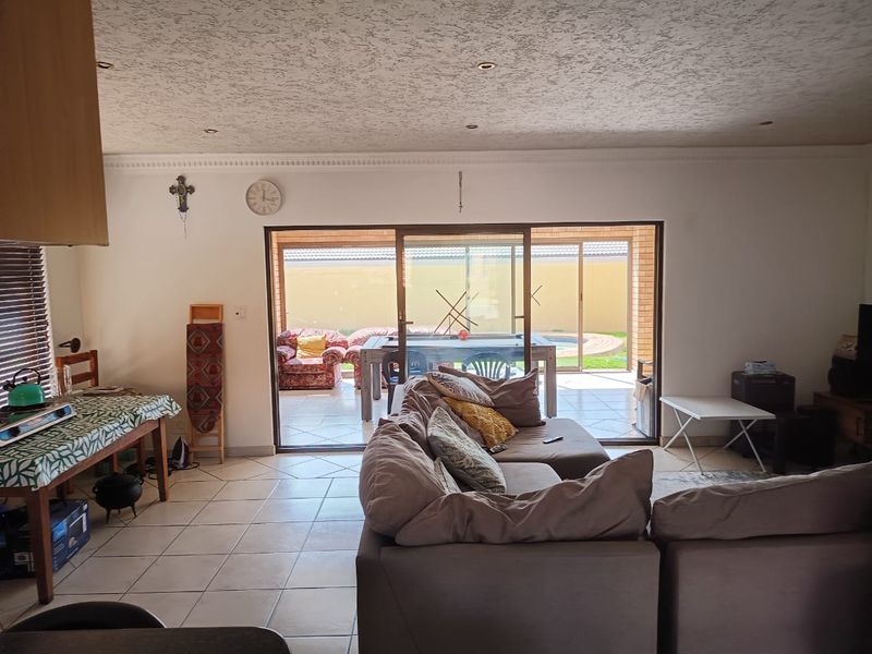 Open-plan living area featuring tiled floors, recessed lighting, and large sliding glass doors providing direct access to the outdoor patio and pool area.