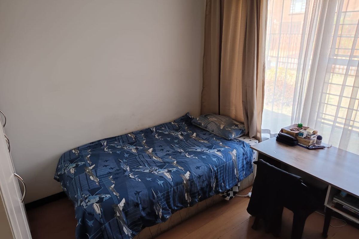 A standard bedroom featuring laminate flooring and large windows with curtain tracks, providing natural light.