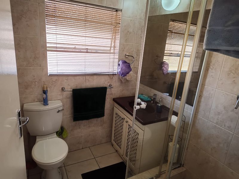 A functional bathroom featuring a shower enclosure, vanity cabinet with basin, and tiled finishes throughout.