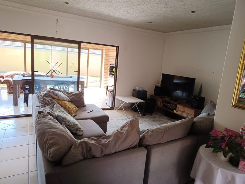 A living room featuring tiled flooring, recessed downlights, and large sliding glass doors that provide direct access to an outdoor patio area.