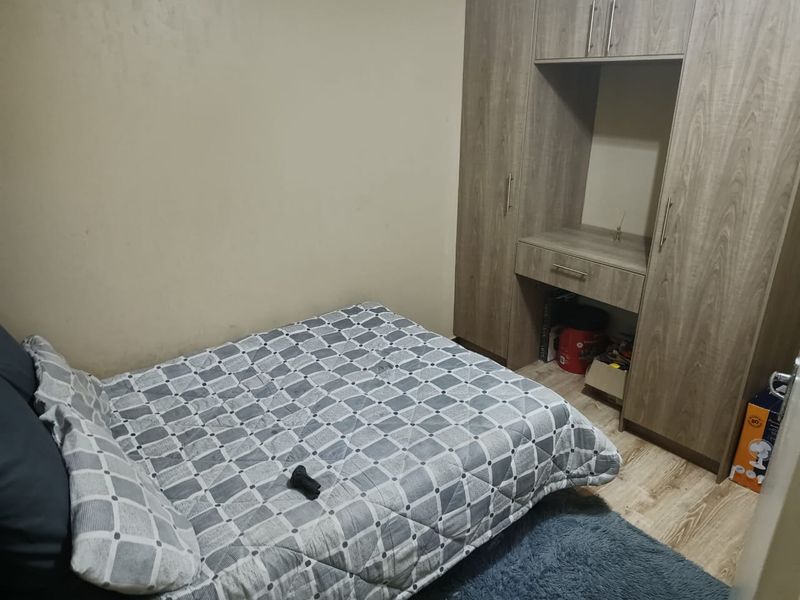 A bedroom featuring wood-grain laminate flooring and a built-in wardrobe with an integrated desk area.