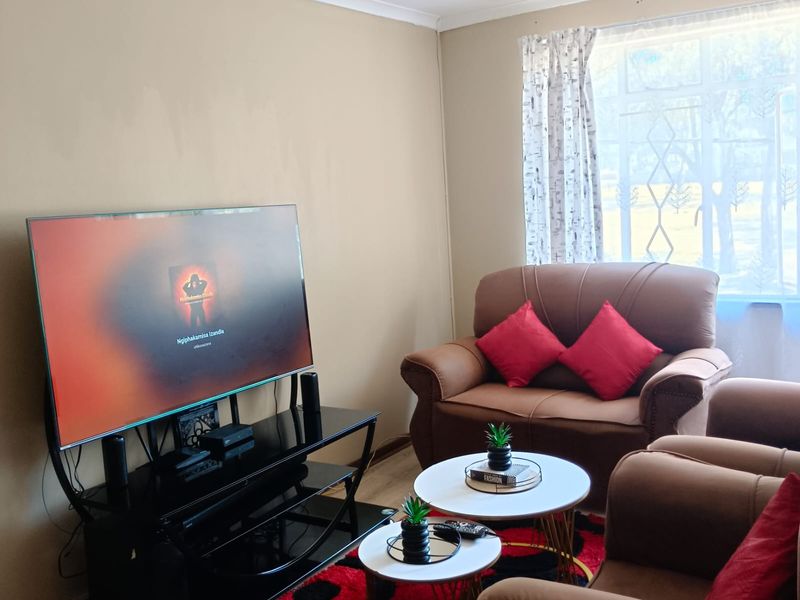 A comfortable living room featuring laminate flooring and a large window that allows for natural light.