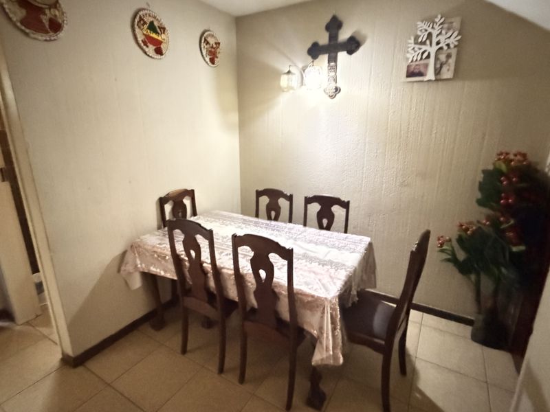 A dining area featuring tiled flooring and wall-mounted lighting, presenting a dated aesthetic that could benefit from modern updates and finishes.