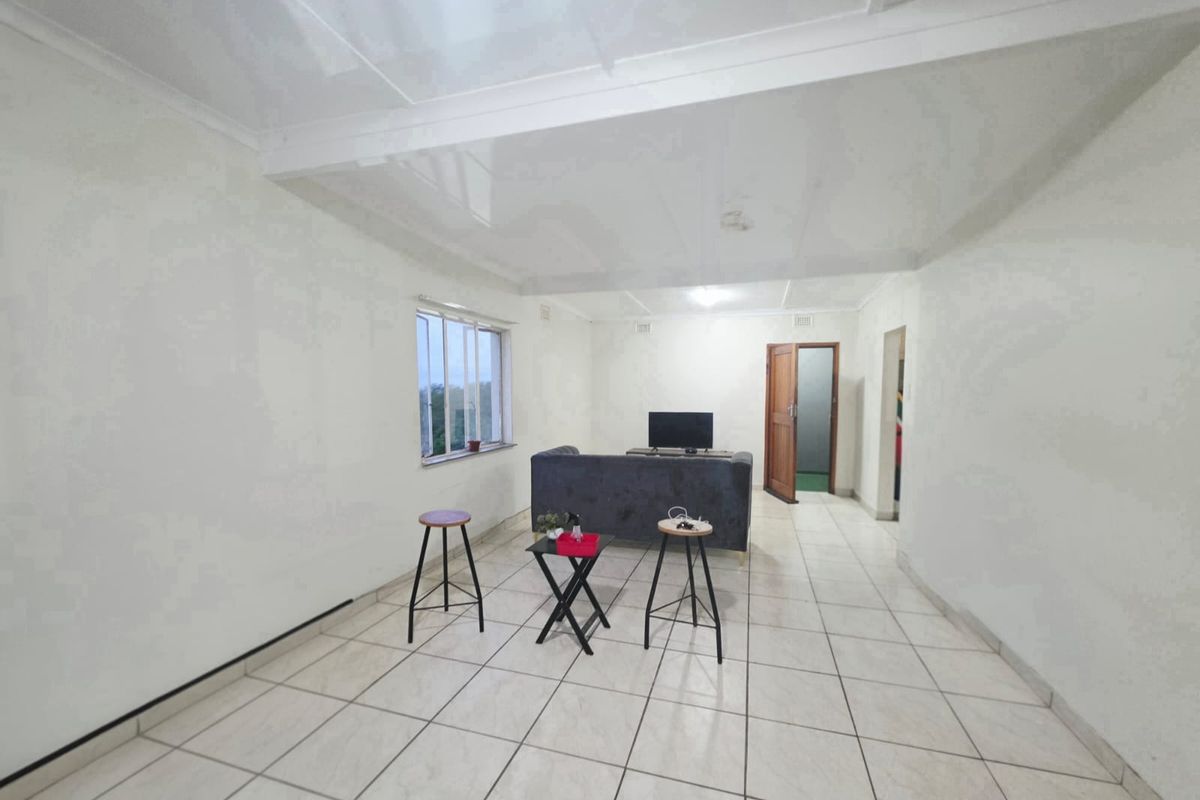 A simple living room featuring white walls, tiled flooring, and a glossy ceiling, providing a neutral base for potential interior design updates.