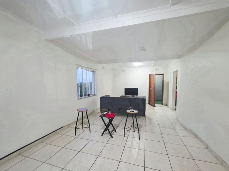 A simple living room featuring white walls, tiled flooring, and a glossy ceiling, providing a neutral base for potential interior design updates.