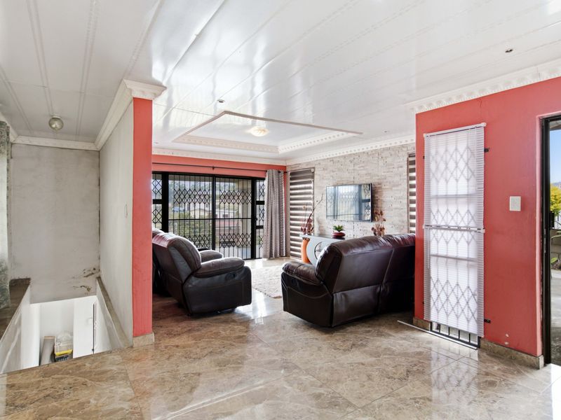 Spacious living room featuring tiled floors, an exposed brick feature wall, and direct access to an outdoor area through sliding security doors.