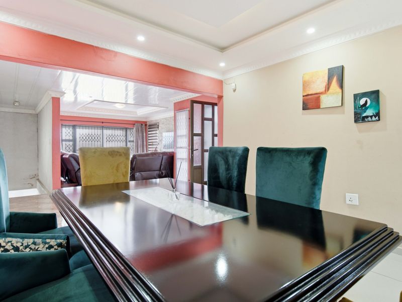 A dining room featuring tiled flooring, recessed ceiling lighting, and decorative cove molding, with an open-plan layout connecting to the adjacent living area.