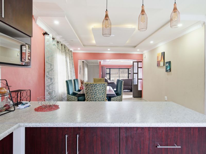 Open-plan kitchen and dining area featuring modern cabinetry, stone countertops, and decorative pendant lighting with a spacious, connected layout.