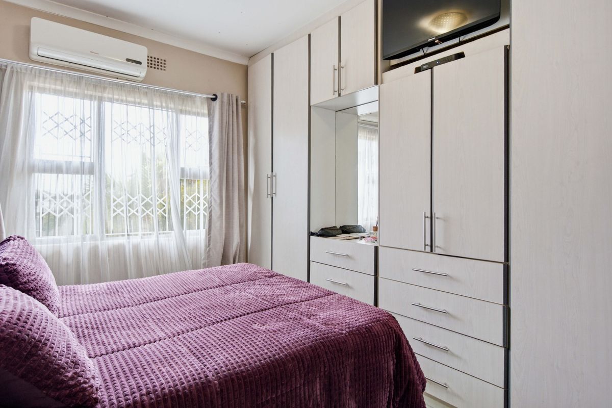 A well-maintained bedroom featuring extensive built-in cabinetry with integrated storage and a wall-mounted air conditioning unit.