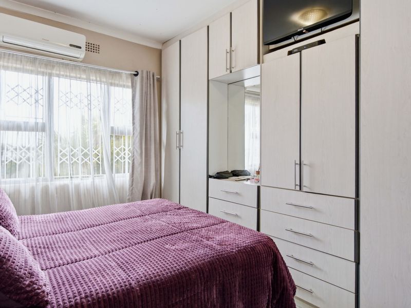 A well-maintained bedroom featuring extensive built-in cabinetry with integrated storage and a wall-mounted air conditioning unit.