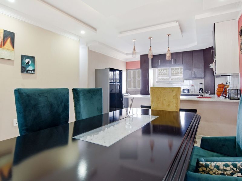 An open-plan dining and kitchen area featuring modern cabinetry, stone countertops, and elegant pendant lighting, creating a cohesive and functional living space.
