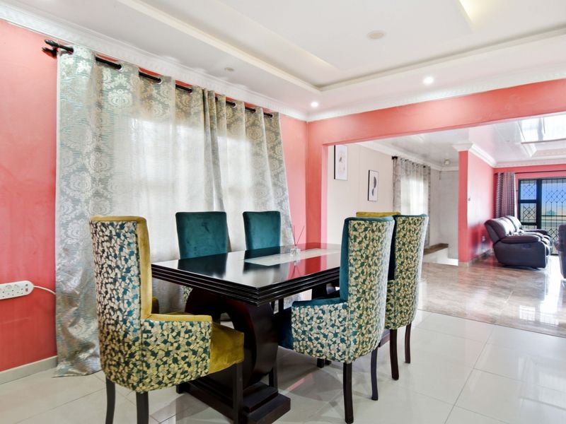 A dining area featuring tiled flooring, recessed ceiling lighting, and decorative cove molding, flowing into an adjacent living space with security gate access.
