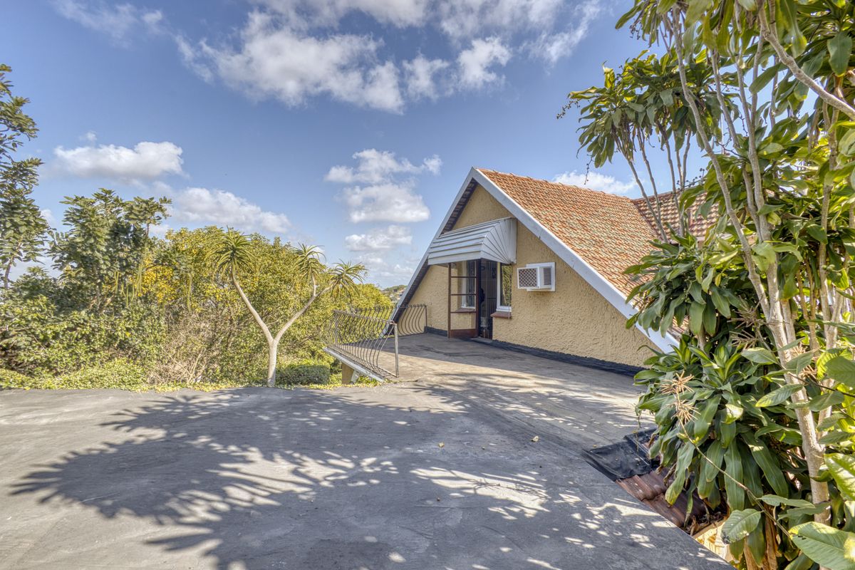 Rear exterior view of the property featuring a concrete patio, wrought iron railing, and a pitched roof with terracotta tiles.