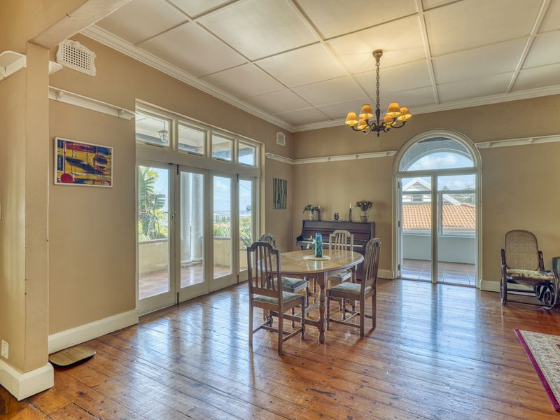 Spacious dining room featuring original hardwood flooring, classic coffered ceilings, and multiple sets of French doors providing access to the outdoor balcony area.