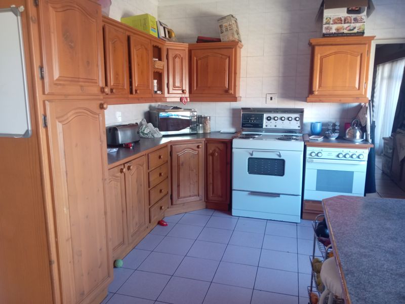 A dated kitchen featuring traditional wooden cabinetry, tiled flooring, and a freestanding stove, offering significant potential for a modern renovation.