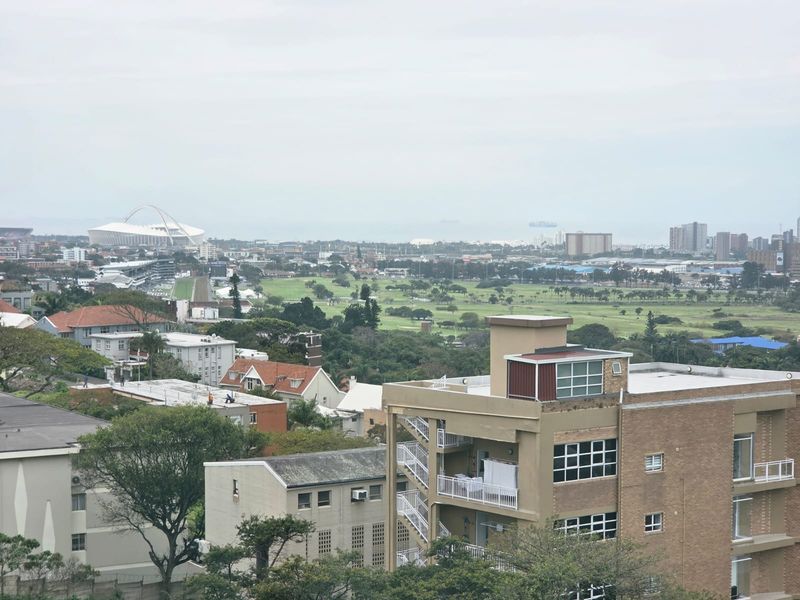 Elevated panoramic view overlooking the surrounding urban landscape, golf course, and distant stadium.