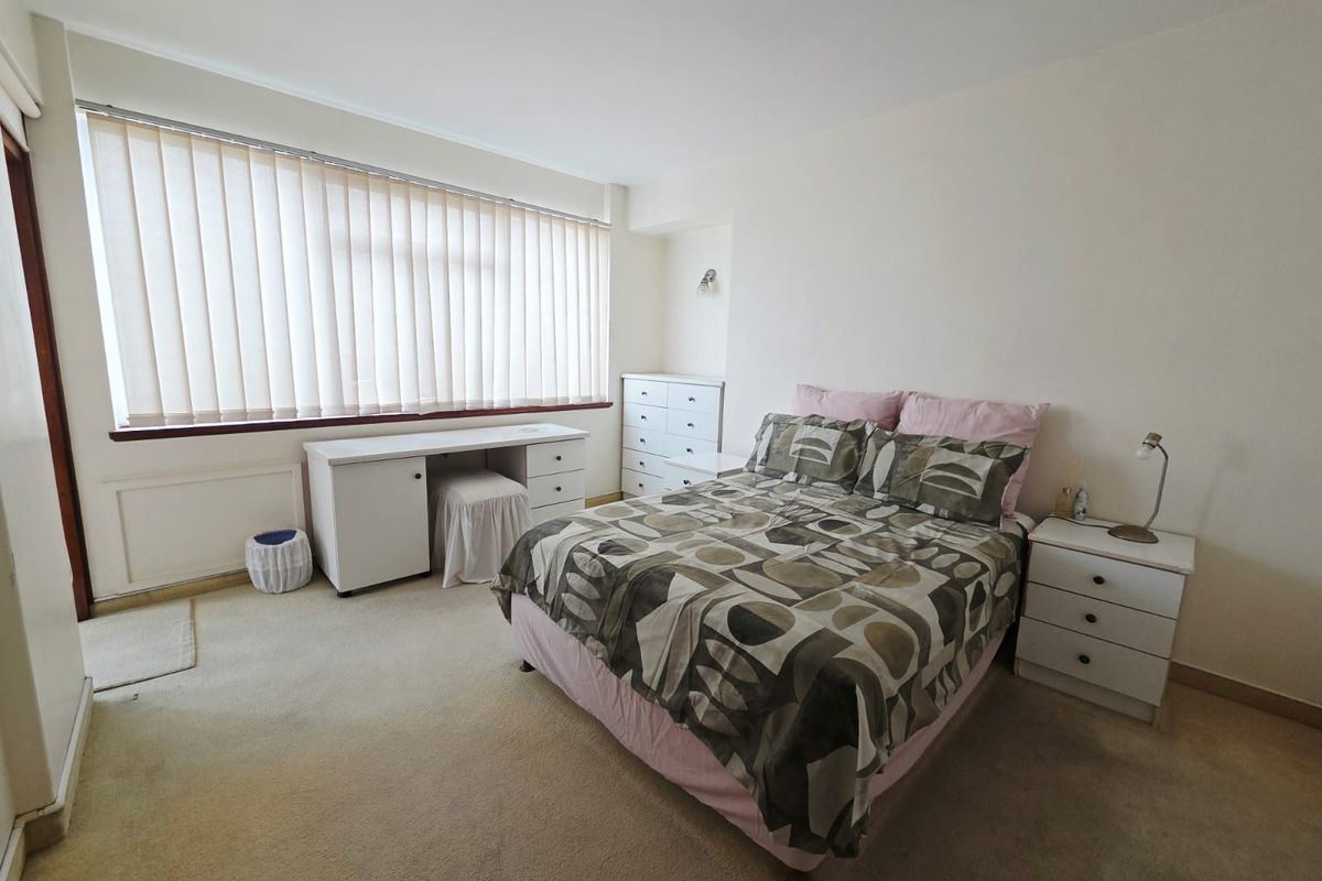 A bedroom featuring neutral walls, carpet flooring, and vertical blinds, offering a functional space with potential for cosmetic updates.