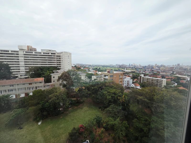 Elevated urban view overlooking surrounding residential apartment buildings and lush green canopy.
