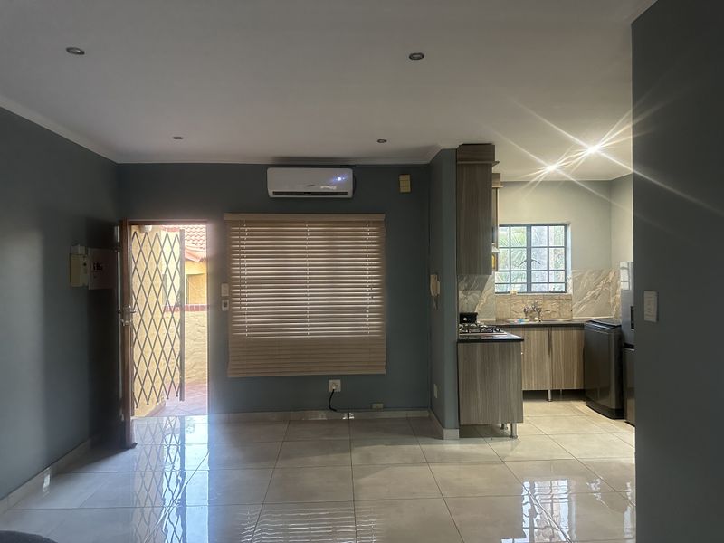 Open plan living area and kitchen featuring tiled floors, recessed lighting, air conditioning, and modern kitchen cabinetry with a gas hob.