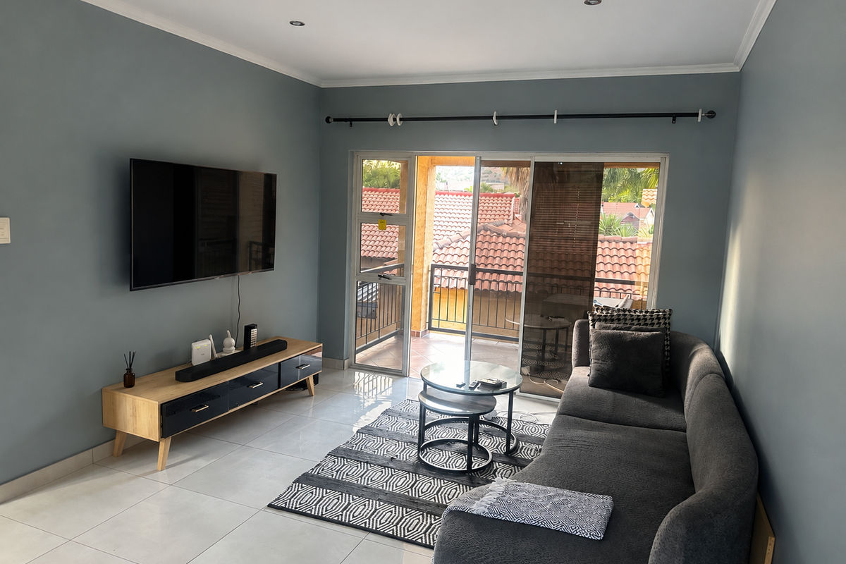 A well-maintained living room featuring tiled flooring, recessed lighting, and a sliding glass door providing direct access to a private balcony.