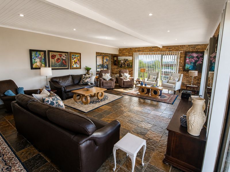 Spacious living room featuring slate tile flooring, an exposed brick feature wall, and a beadboard ceiling with recessed lighting, opening to an outdoor area.
