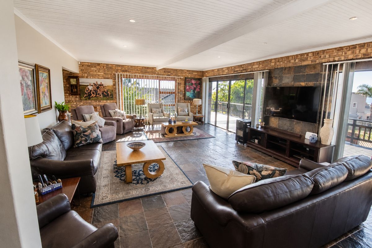 Spacious living room featuring exposed brick walls, slate tile flooring, and a tongue and groove ceiling with direct access to an outdoor deck.