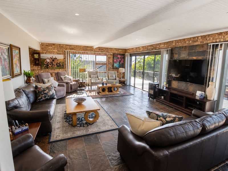 Spacious living room featuring exposed brick walls, slate tile flooring, and a tongue and groove ceiling with direct access to an outdoor deck.