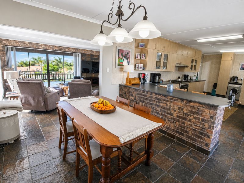 Open-plan living and kitchen area featuring slate flooring, a brick breakfast bar, and direct access to a balcony through sliding glass doors.