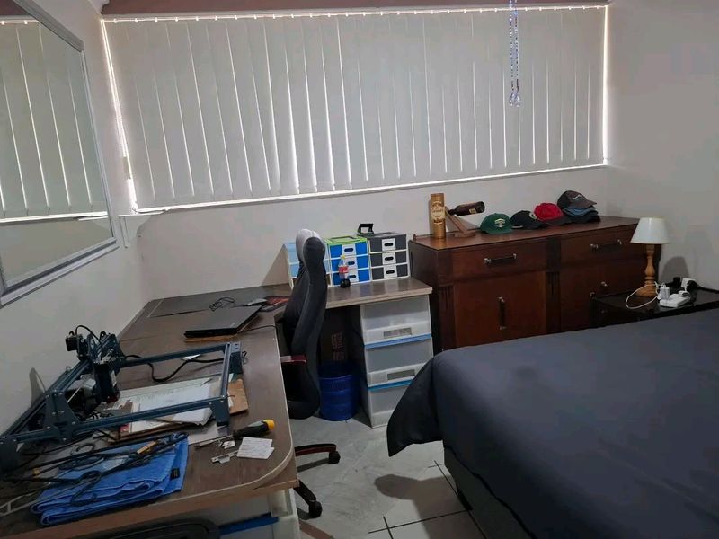 A bedroom featuring tiled flooring and vertical blinds, providing a functional space with natural light.