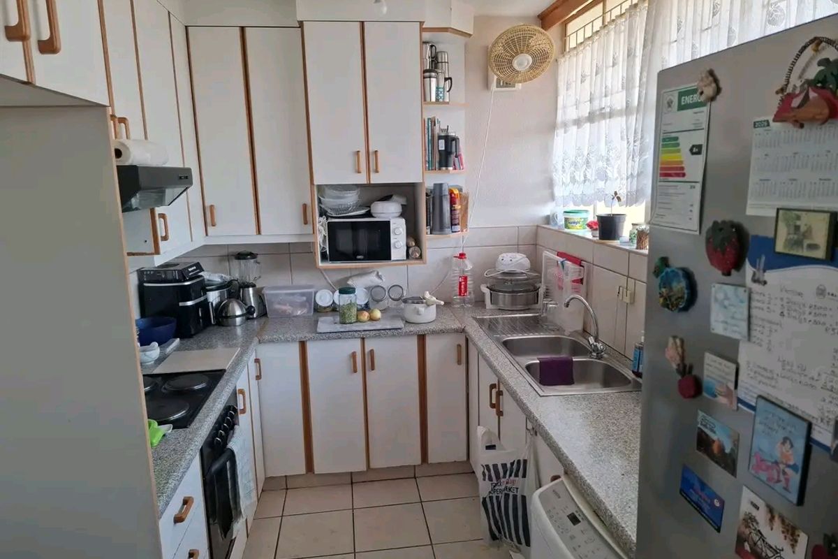 A functional kitchen featuring laminate cabinetry, granite countertops, a double basin sink, and tiled finishes, offering a practical layout for daily meal preparation.