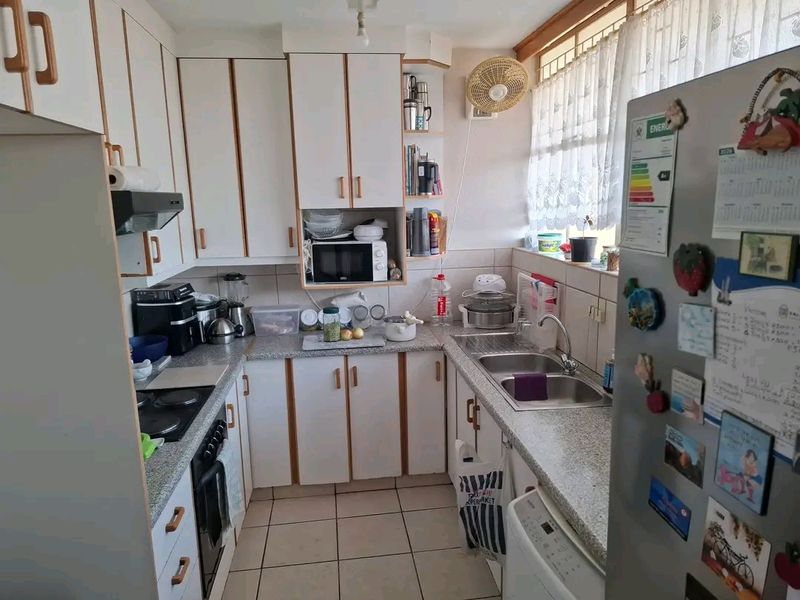 A functional kitchen featuring laminate cabinetry, granite countertops, a double basin sink, and tiled finishes, offering a practical layout for daily meal preparation.