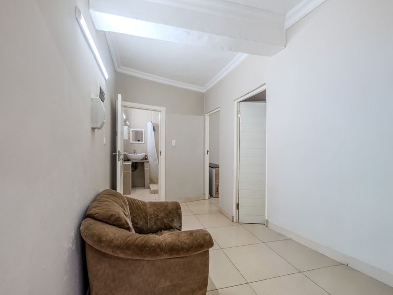 A functional hallway with tiled flooring and access to adjacent rooms, featuring neutral wall tones and simple architectural detailing.